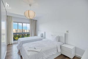 ein weißes Schlafzimmer mit zwei Betten und einem großen Fenster in der Unterkunft Host Prime Grand Apartment in New cairo