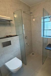 a bathroom with a toilet and a glass shower at White Sands Resort & Spa in Varca