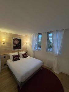 a bedroom with a large white bed with two windows at Le Troyes Coeur in Troyes