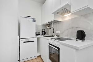een witte keuken met een wastafel en een koelkast bij Five Bedroom Apartment for 12 in Gdańsk Center with Desk and Balcony by Noclegi Renters in Suchanino