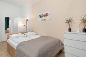 een witte slaapkamer met een bed en een ladekast bij Five Bedroom Apartment for 12 in Gdańsk Center with Desk and Balcony by Noclegi Renters in Suchanino
