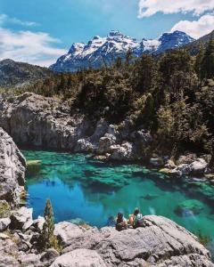 due persone sedute su una roccia vicino a uno specchio d'acqua di María de la Patagonia a Trevelin
