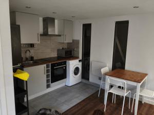 una pequeña cocina con mesa y lavadora en Studio house, en Bickley 7 fotos más