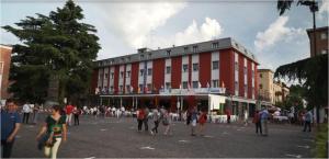 grupa ludzi stojących przed czerwonym budynkiem w obiekcie Hotel Domus w mieście Maranello
