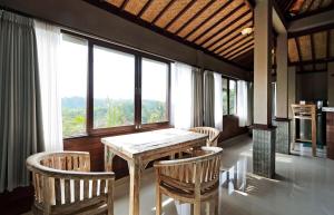 a wooden table and chairs in a room with windows at Huge Amazing Campuhan Ridge Walk view room in Ubud +16 photos