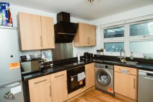 a kitchen with wooden cabinets and a washer and dryer at Modern 2 bedroom Terrace in Woolwich