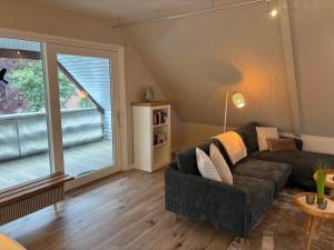 Una sala de estar con un sofá y una ventana grande. en Balkon Hüs, en Alkersum