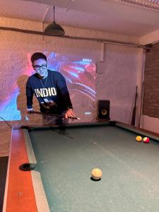 a man is standing over a pool table at Hostel Bohemian in Montevideo