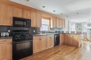 a kitchen with wooden cabinets and black appliances at Luxury NY Home with Game Room and Free Parking in White Plains +9 photos
