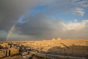 a rainbow over the pyramids and a city with buildings at Atlantis Palace Pyramids View in ‘Ezbet `Abd el-Ḥamîd
