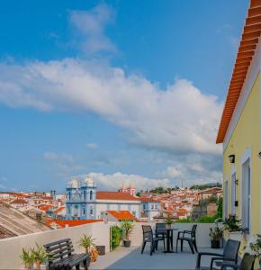 ein Balkon mit Stühlen und Tischen mit Blick auf eine Stadt in der Unterkunft Yellow House - Casa 2 in Angra do Heroísmo