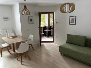 a living room with a table and a green couch at Triglav NP Apartment - above Bled in Zgornje Gorje