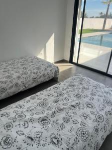 une chambre avec deux lits et une grande fenêtre dans l'établissement Villa Les Palmiers, à Temlale 25 autres photos