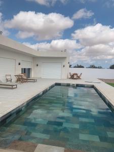 une piscine avec deux chaises et un bâtiment dans l'établissement Villa Les Palmiers, à Temlale