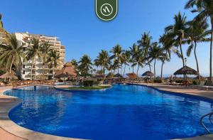 une grande piscine bleue avec des palmiers et des bâtiments dans l'établissement Amazing Studio with Terrace Overlooking the Ocean, à Nuevo Nayarit