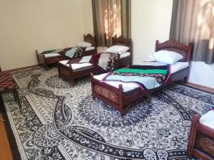 een kamer met vier bedden, stoelen en een kleed bij Qokhna Samarqand in Samarkand +5 foto's