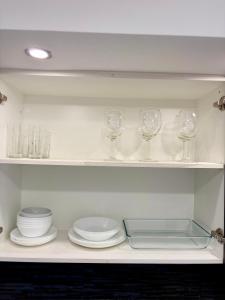 a kitchen with plates and wine glasses on a shelf at StaySanto in Loures in Loures
