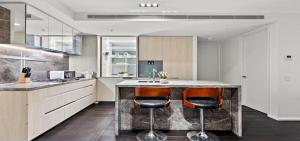 una cucina con una grande isola con due sgabelli da bar di Lakeside Luxury 2-Bedroom Apartment in Albert Park with Pool, Gym & Parking a Melbourne