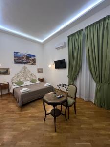 a bedroom with a bed and a table and green curtains at Di Palma Suite in Naples