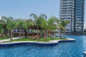 a swimming pool with palm trees and a building at Holiday Apartments at Grand Sapphire Residence in Saint Yeorgios