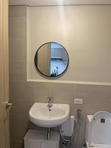 Un baño con lavabo y espejo sobre el inodoro. en ABE Place, en Cebú