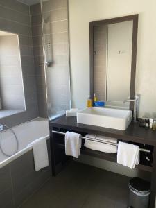 a bathroom with a sink and a tub and a mirror at Hotel du Fronton in Bidart +20 photos