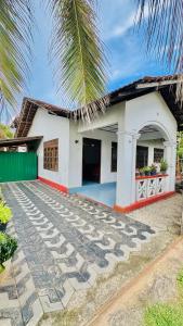 una casa blanca con una palmera delante en Aurora Villa, en Ratgama Hegoda