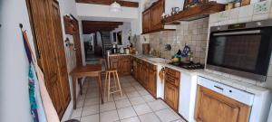 a kitchen with wooden cabinets and a large screen tv at Maison authentique dans les Gorges du Tarn in Montbrun