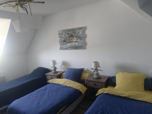 two beds in a room with blue sheets and yellow pillows at Le Chant des Vagues in Audinghen