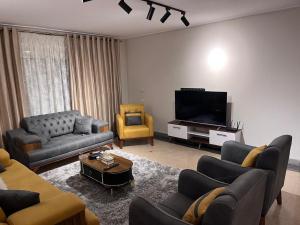 a living room with couches and a flat screen tv at A Luxury Hotel Appartment at NEW GIZA Imperial Compound قريبة جدا للمتحف المصري الجديد in Abū Rawwāsh