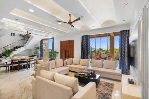 a living room with a couch and a table at Shreya Blossom Retreat 4-BHK Retreat With Private Pool, Gazebo, Garden, Bar & Scenic Aravali Views in Thūr