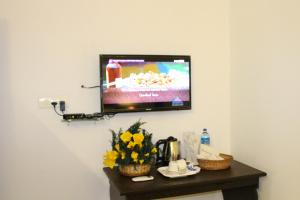 a television on a wall with flowers on a table at Ebenezer Plaza in Nedumbassery