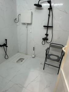 a white bathroom with a toilet and a chair in it at جمعتنا in Al Qā‘id