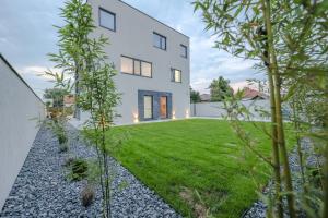 a white house with a yard with grass at Apartment Cocosinella in Surčin