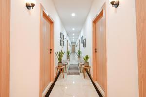 ハイデラバードにあるFabHotel Narsingi - Nr Global Eye Hospital, Narsingiの白い壁と木製のドアと鉢植えの植物のある廊下