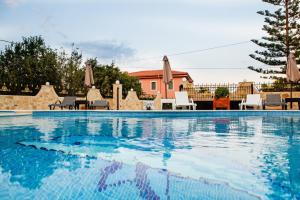 a swimming pool with chairs and a house in the background at Diwani Luxury Villas in Lixouri