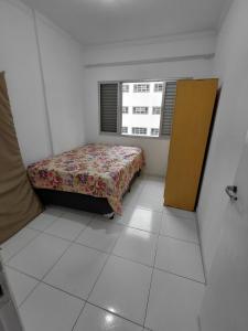 Un dormitorio pequeño con una cama y una ventana. en Apartamento Mirim, en Praia Grande 2 fotos más