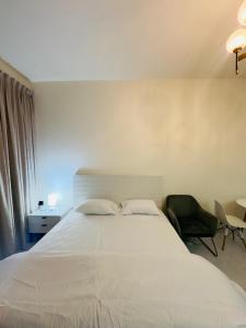 a bedroom with a large white bed and a chair at Mahenti - Lawnz · Well furnished apt with balcony in Dubai +4 photos