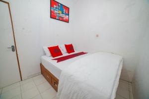 - une chambre avec un lit blanc et des oreillers rouges dans l'établissement Halona Taraman Guest House by Yurooms, à Ngemplak