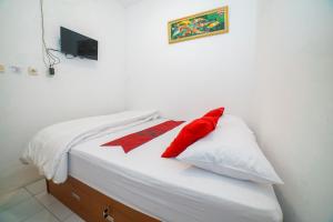 un lit avec des oreillers rouges et blancs dessus dans l'établissement Halona Taraman Guest House by Yurooms, à Ngemplak