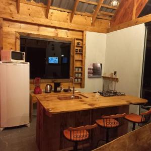 a kitchen with a sink and a counter with stools at Cabana Rustica com Hydro, Recanto das Trutas, SC in Bocaina do Sul