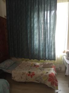 a bedroom with a bed and a window with curtains at Комната рядом с Дерибасовской in Odesa