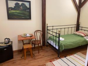 a bedroom with a bed and a small table at Karczma Siedlisko Pokoje Gościnne 