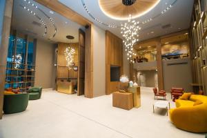 a lobby with yellow furniture and a chandelier at Blue Sky Apart-Hotel Batumi in Batumi
