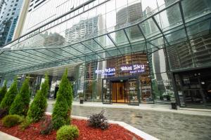 a glass building with a sign in front of it at Blue Sky Apart-Hotel Batumi in Batumi