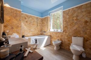 a bathroom with a tub and a toilet and a sink at Villa Valery - pajūrio dvasia dvelkianti oazė in Kupriai +24 photos