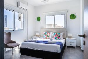 a bedroom with a bed with a chair and two windows at Phoenix 2-Bedroom Apartment in Larnaca +10 photos