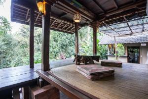 an outdoor deck with a bench and a table at Secluded jungle villa w private pool & serene view in Ubud