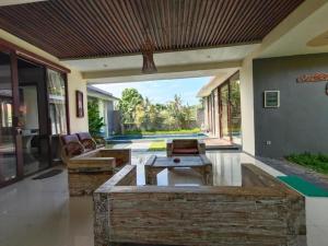 Una sala de estar abierta con mesas de madera y un patio. en Asri Sari Ubud Resort, en Ubud