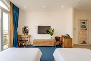 Una habitación de hotel con dos camas y un televisor. en SMN Homestay, en Tân Thành (1)